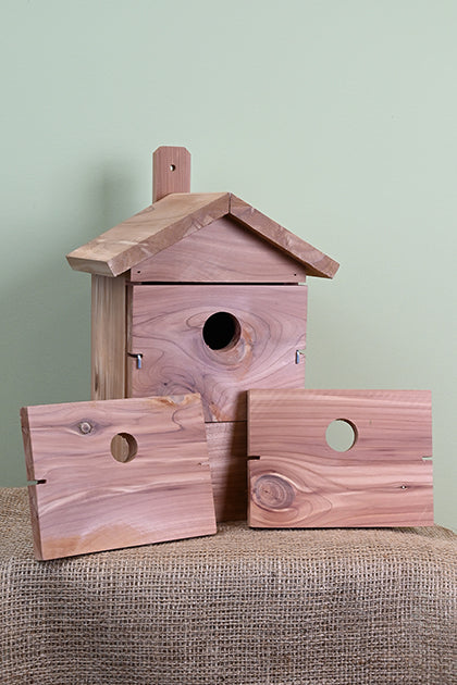 Red cedar wood construction. Rectangular shaped house. 3 pieces of wood, each with a different hole size.