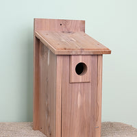 Red cedar wood construction. Tall rectangular shape. Hole for the birds is in the top centre of the bird house.