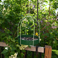 Feeder is hanging outdoors while a gold finch enjoys the seeds.