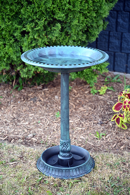 Green birdbath outside in a garden.