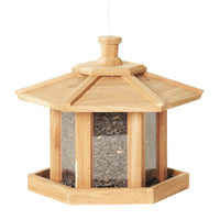 Beige wooden gazebo shaped bird feeder that is filled with seeds.