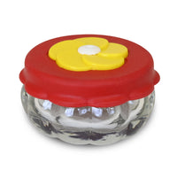 Small circular jar, red lid with a yellow flower shaped feeding hole.