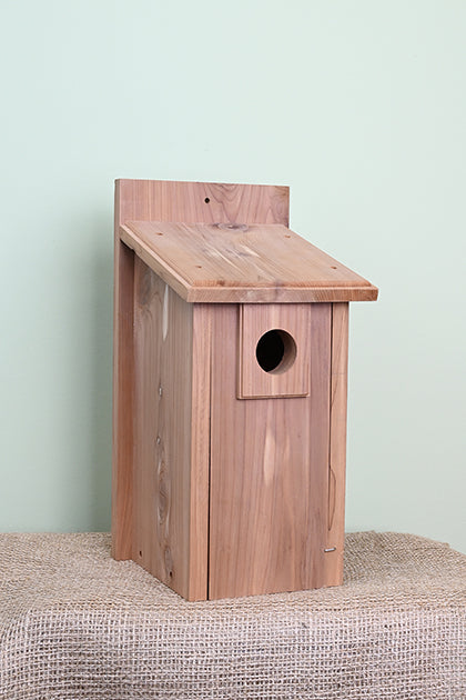 Red cedar wood construction. Tall rectangular shape. Hole for the birds is in the top centre of the bird house.