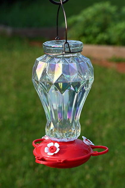 Iridescent bottle in the shape of a vase. The base is red poly material with white flower feeding ports.