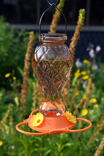 Orange glass bottle with diamond shape. Orange poly base with yellow flower feeding ports. 