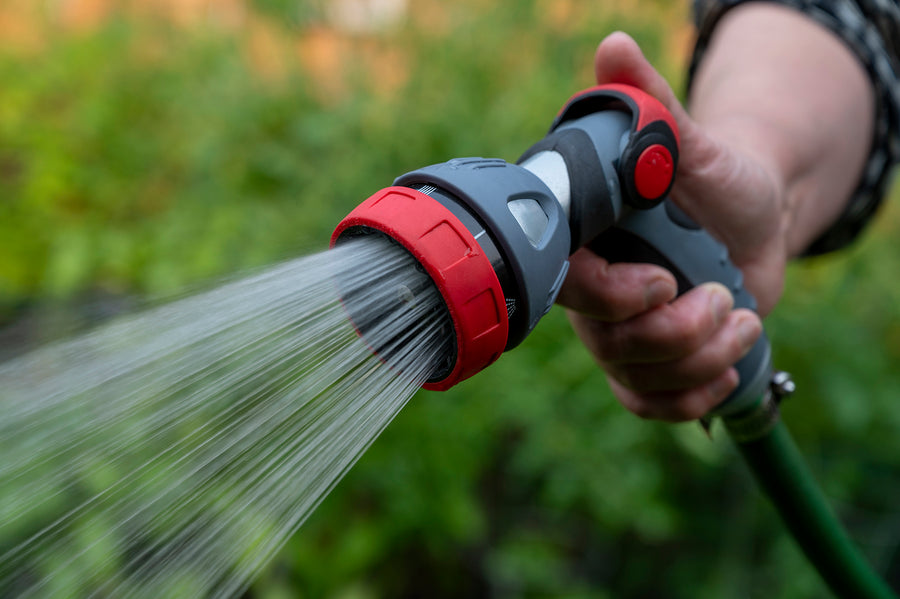 Water nozzle spraying water onto a garden, it is attached to a hose.