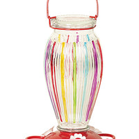 Glass vase shape. Purple, red, yellow, green, and blue stripes on the glass. Red circular base with white flower shaped feeding holes.